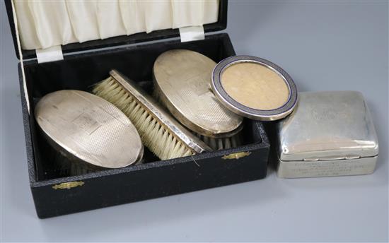 A white metal and enamel circular photograph frame, a silver cigarette box and three silver mounted brushes.